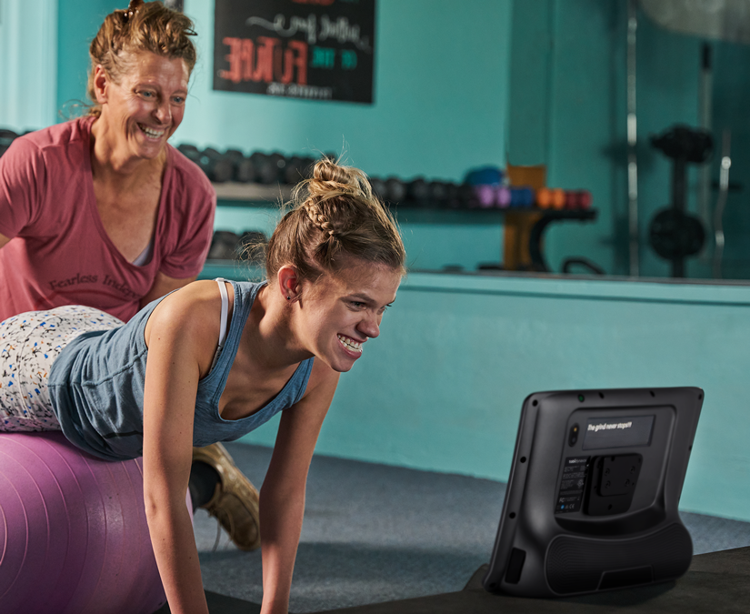 Frau, die im Fitnessstudio ihr Assistenzgerät der Tobii Dynavox TD I-Series verwendet